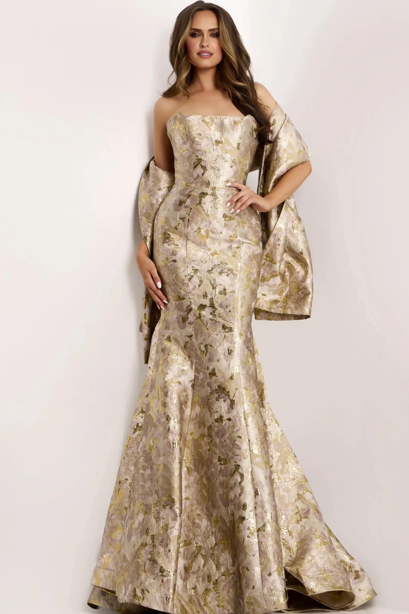A woman wearing a strapless, gold and floral-patterned evening gown with a draped shawl.